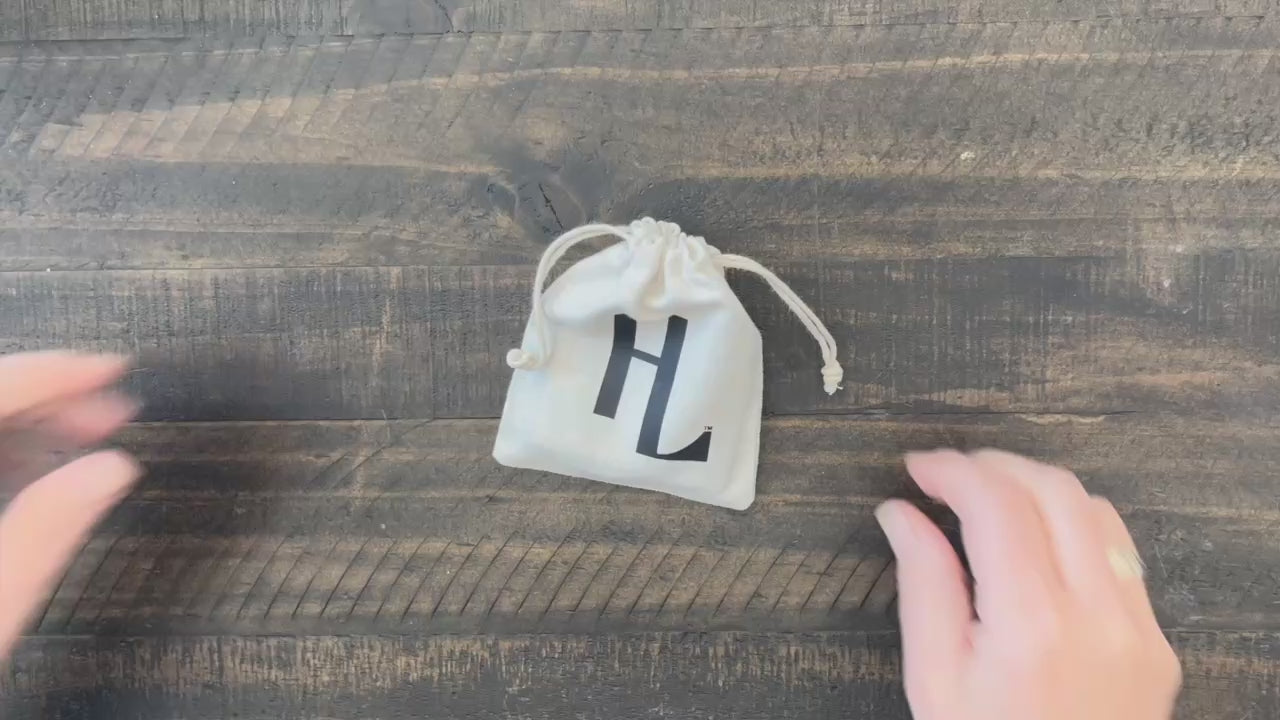 Hands displaying brown leather Christian bracelet engraved with HE LIVES message.