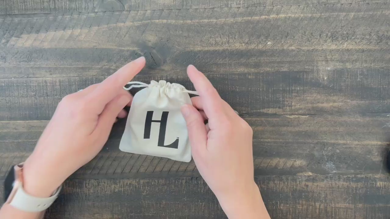 Hands pulling light brown leather He Lives bracelet for men from pouch