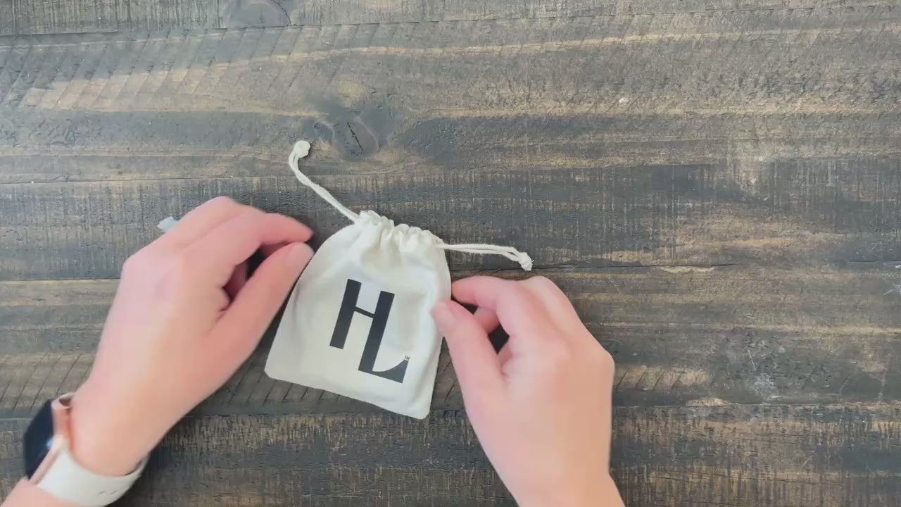 Christian bracelet in black leather with black clasp shown being pulled from HE LIVES pouch.