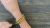 Close-up video of four stacked gold beaded Christian bracelets
