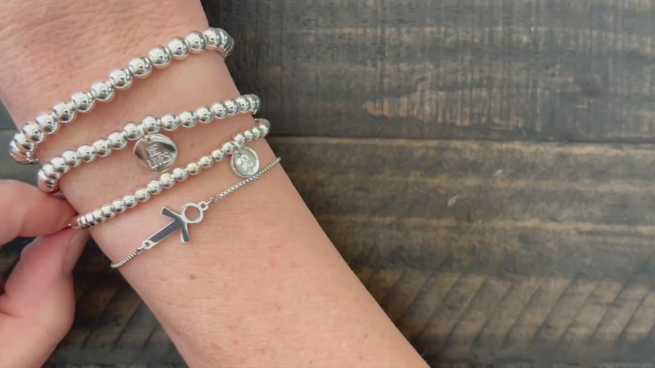 Stacked silver bead bracelets with He Lives charm and resurrected Jesus symbol